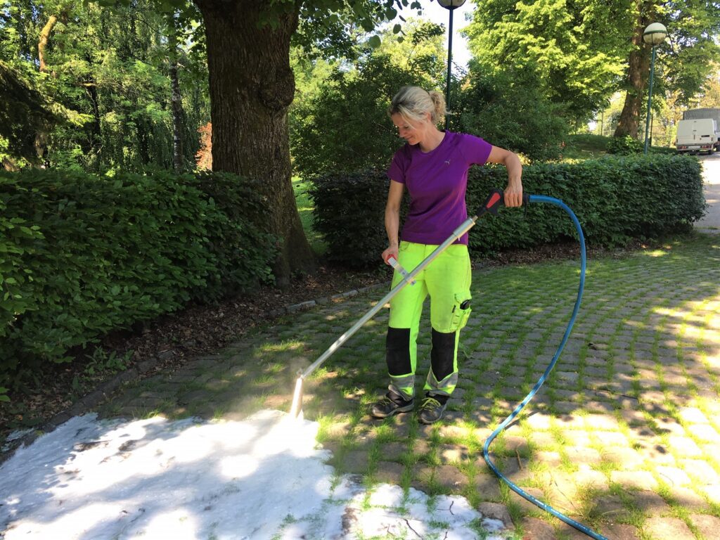 A female employee from the landscape gardener Svein Boasson A / S spreads the thermal pesticide SPUMA over some cobblestones.